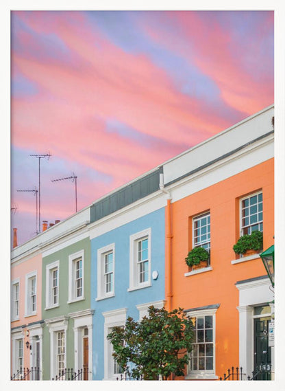 A row of colorful pastel townhouses in shades of orange, blue, green, and pink, viewed from a low angle against a dramatic, cloudy pink and purple sunset sky. Poster