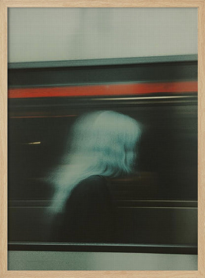 An abstract photograph with motion blur, featuring the ghostly silhouette of a person's head and shoulders in pale blue. The dark background is streaked with horizontal lines of red and white light, suggesting the speed of a passing train or subway. Wall Art