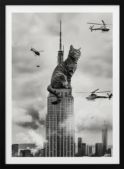 A surreal black and white image depicting a giant tabby cat sitting on top of the Empire State Building, similar to King Kong. Helicopters fly around the colossal cat against a cloudy New York City skyline. Decor
