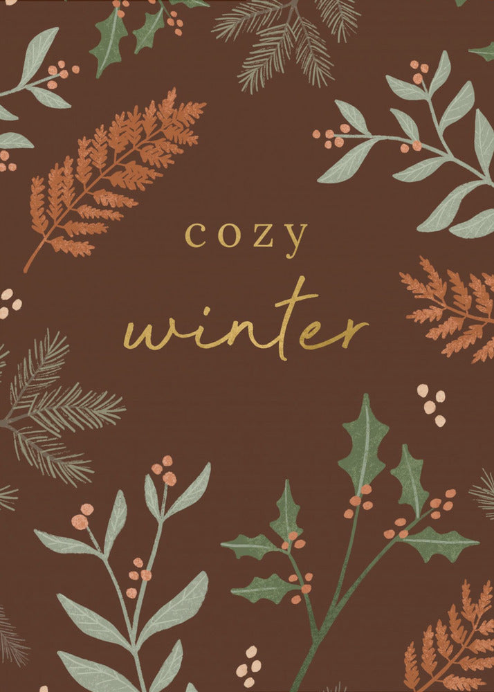 A warm, illustrative poster with a dark brown background featuring the words 'cozy winter' in gold script at the center. The text is framed by a wreath of winter botanicals, including holly, pine needles, and ferns in shades of green and burnt orange. Print