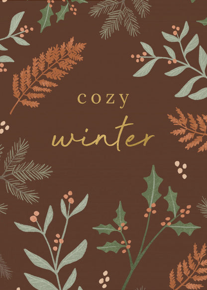A warm, illustrative poster with a dark brown background featuring the words 'cozy winter' in gold script at the center. The text is framed by a wreath of winter botanicals, including holly, pine needles, and ferns in shades of green and burnt orange. Print