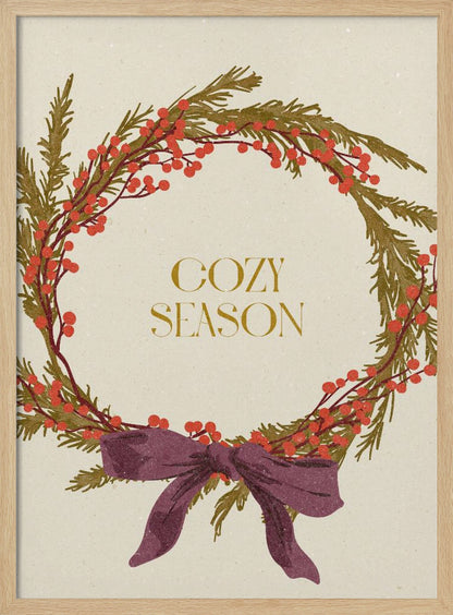 A vintage-style illustration of a festive wreath made of green boughs and red berries, tied with a large purple bow at the bottom. The text 'COZY SEASON' is written in gold inside the wreath on a cream-colored background, all enclosed in a thin black frame. Wall Art