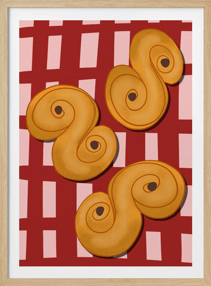 A vibrant illustration of three golden-yellow S-shaped pastries, resembling Swedish saffron buns, resting on a red and pink checkered tablecloth. The artwork is presented within a black frame. Decor