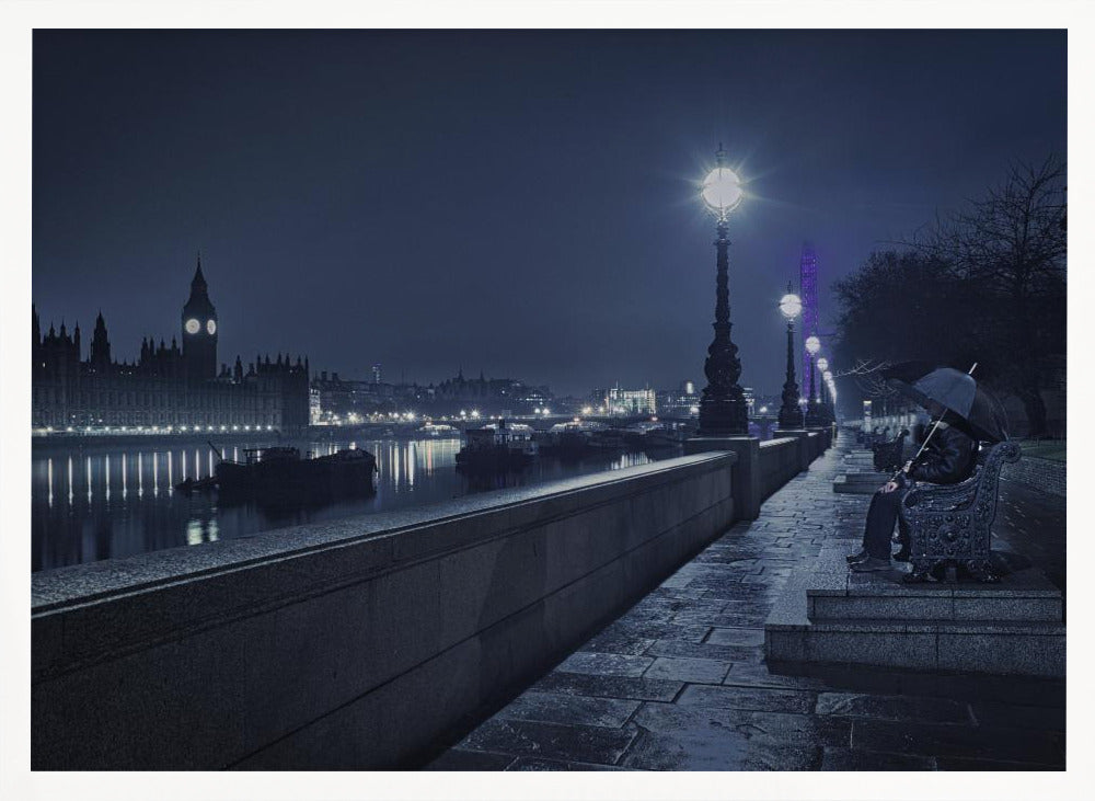 A moody, blue-toned night photograph of London. A solitary figure sits on a bench under an umbrella on a wet stone walkway along the River Thames, illuminated by vintage streetlights. Across the river, the iconic Houses of Parliament and Big Ben are lit up against the dark sky, their lights reflecting in the water. Poster