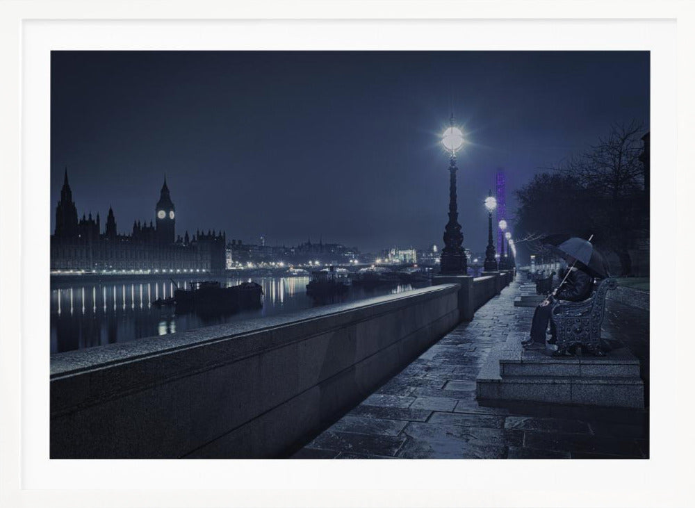 A moody, blue-toned night photograph of London. A solitary figure sits on a bench under an umbrella on a wet stone walkway along the River Thames, illuminated by vintage streetlights. Across the river, the iconic Houses of Parliament and Big Ben are lit up against the dark sky, their lights reflecting in the water. Poster