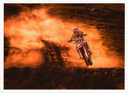 An action-packed photo of a motocross rider in mid-air, jumping their dirt bike over a mound of earth. A large cloud of orange dust billows behind them, creating a dramatic and fiery background. Wall Art