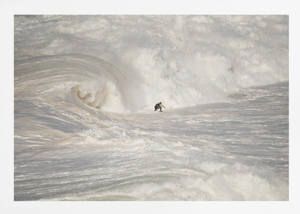 A framed photograph of a lone surfer dwarfed by a massive, powerful ocean wave. The water is a churning mass of white foam and spray, and the surfer is navigating the enormous swell. Print