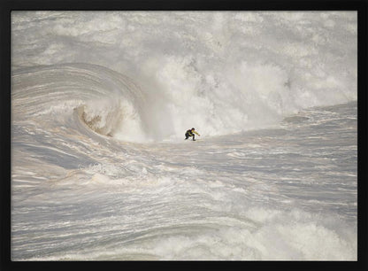A framed photograph of a lone surfer dwarfed by a massive, powerful ocean wave. The water is a churning mass of white foam and spray, and the surfer is navigating the enormous swell. Print