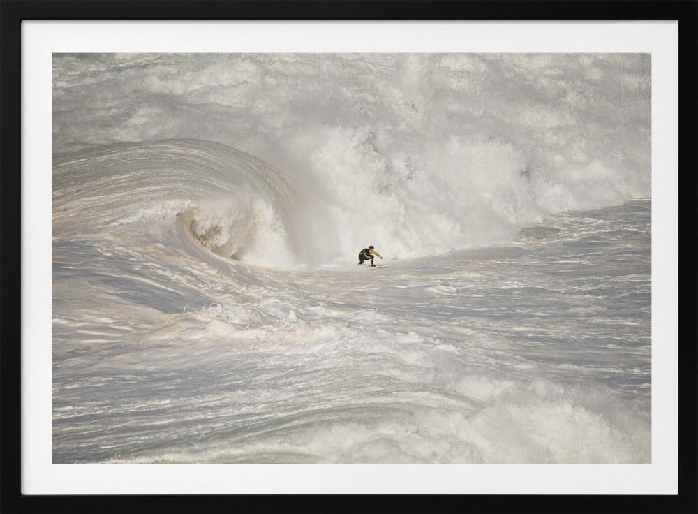 A framed photograph of a lone surfer dwarfed by a massive, powerful ocean wave. The water is a churning mass of white foam and spray, and the surfer is navigating the enormous swell. Print