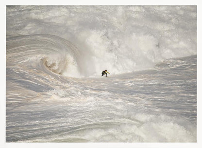 A framed photograph of a lone surfer dwarfed by a massive, powerful ocean wave. The water is a churning mass of white foam and spray, and the surfer is navigating the enormous swell. Print