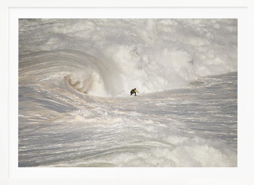 A framed photograph of a lone surfer dwarfed by a massive, powerful ocean wave. The water is a churning mass of white foam and spray, and the surfer is navigating the enormous swell. Print