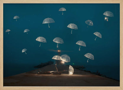 A surreal night scene with a person lying on a pier next to a glowing, transparent umbrella, while numerous other glowing umbrellas float like jellyfish in the dark blue sky above the sea, with a distant lighthouse in the background. Poster