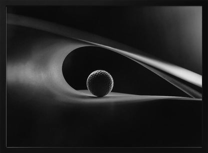 An artistic black and white photograph of a golf ball resting inside the gentle curve of a dark, abstract shape, creating a minimalist and dramatic composition with strong light and shadows. Poster