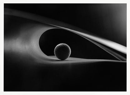 An artistic black and white photograph of a golf ball resting inside the gentle curve of a dark, abstract shape, creating a minimalist and dramatic composition with strong light and shadows. Poster