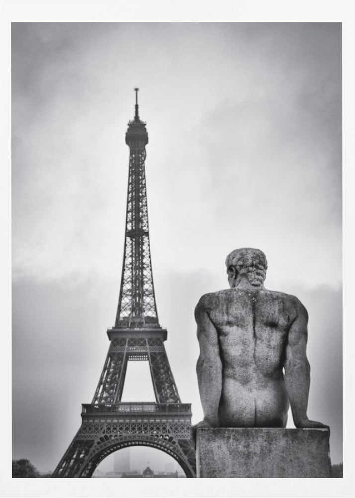 A black and white photograph capturing a contemplative scene in Paris, with the back of a seated, muscular male stone statue in the foreground looking towards the iconic Eiffel Tower which stands tall against a cloudy sky. Print