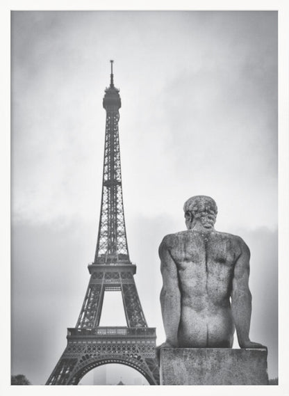A black and white photograph capturing a contemplative scene in Paris, with the back of a seated, muscular male stone statue in the foreground looking towards the iconic Eiffel Tower which stands tall against a cloudy sky. Print