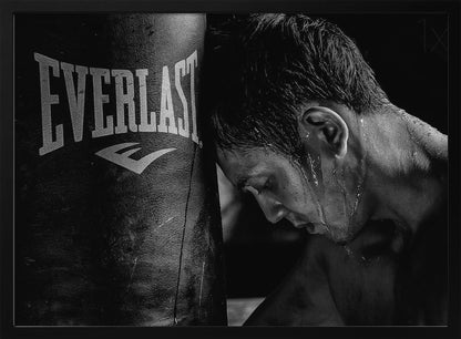 A dramatic black and white close-up photograph of an exhausted boxer resting his head against a heavy Everlast punching bag, with sweat dripping down his face and neck. Poster