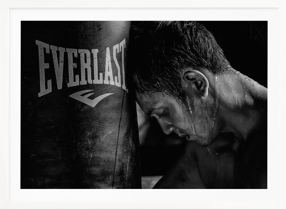 A dramatic black and white close-up photograph of an exhausted boxer resting his head against a heavy Everlast punching bag, with sweat dripping down his face and neck. Poster