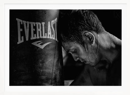A dramatic black and white close-up photograph of an exhausted boxer resting his head against a heavy Everlast punching bag, with sweat dripping down his face and neck. Poster