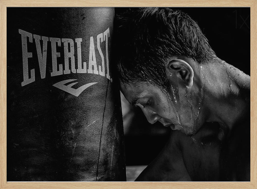 A dramatic black and white close-up photograph of an exhausted boxer resting his head against a heavy Everlast punching bag, with sweat dripping down his face and neck. Poster