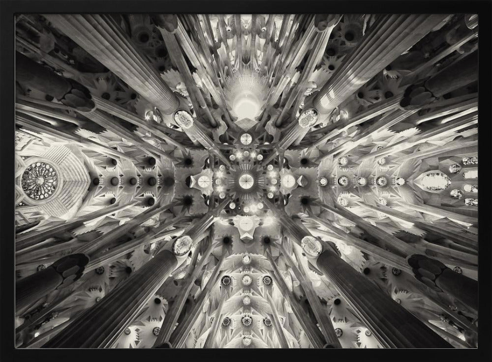 A framed black and white photograph captures the breathtaking, symmetrical ceiling of Gaudí's Sagrada Familia basilica, viewed directly from below. The massive columns rise and branch out like a forest canopy, creating a complex and mesmerizing architectural pattern of vaults, ribs, and skylights. Artwork