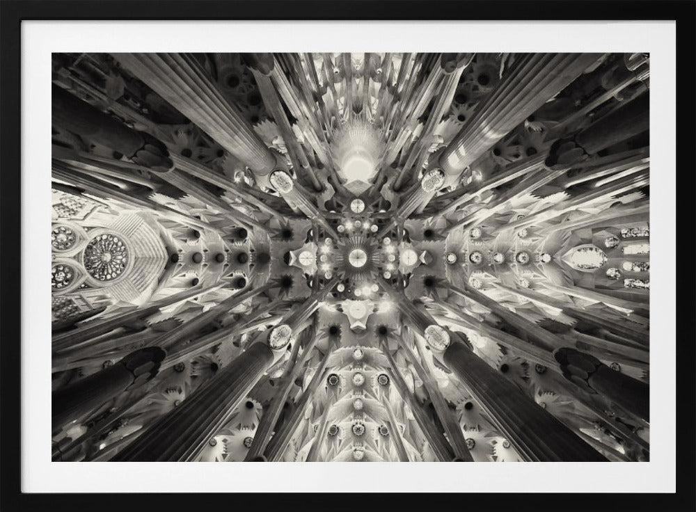 A framed black and white photograph captures the breathtaking, symmetrical ceiling of Gaudí's Sagrada Familia basilica, viewed directly from below. The massive columns rise and branch out like a forest canopy, creating a complex and mesmerizing architectural pattern of vaults, ribs, and skylights. Artwork