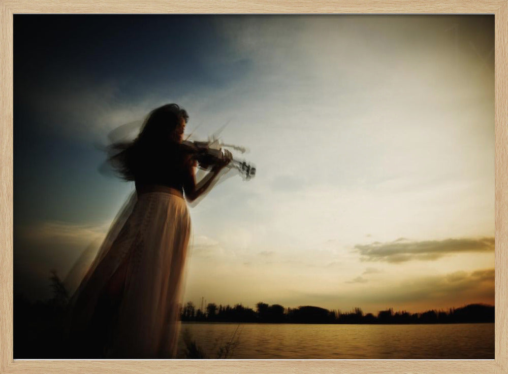 An artistic, framed photograph with motion blur capturing the silhouette of a woman in a long flowing skirt playing the violin by a lake against a dramatic sunset sky. Poster