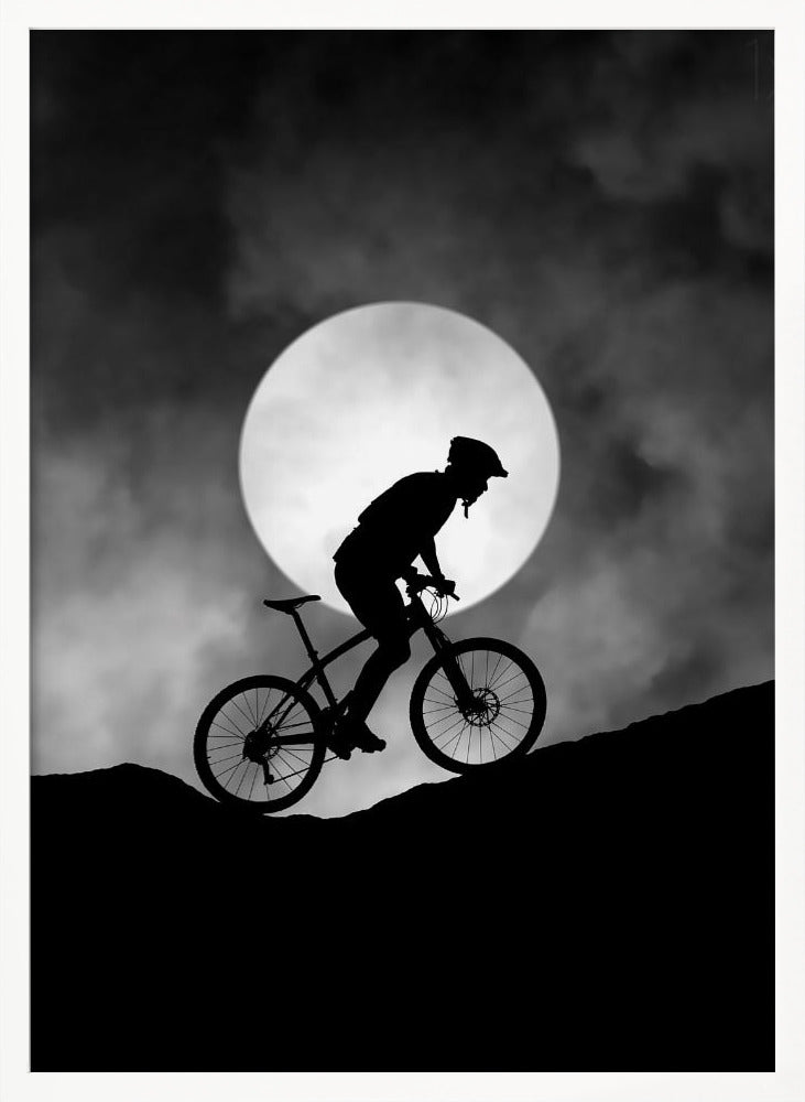 A dramatic black and white silhouette of a mountain biker riding uphill against the backdrop of a large, full moon in a cloudy night sky. Decor