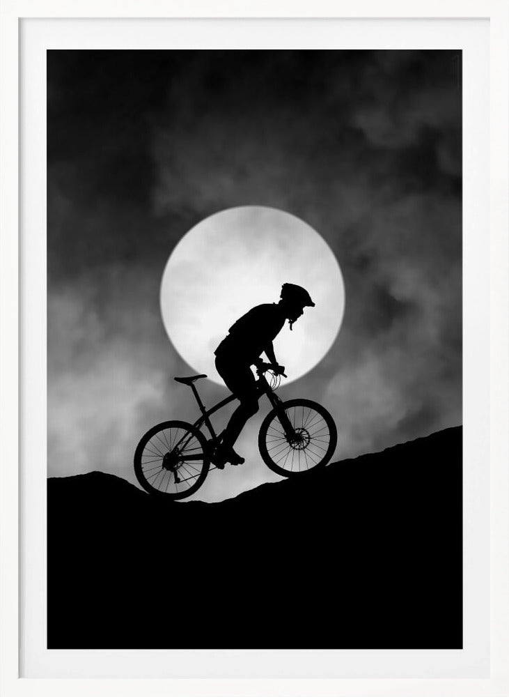 A dramatic black and white silhouette of a mountain biker riding uphill against the backdrop of a large, full moon in a cloudy night sky. Decor