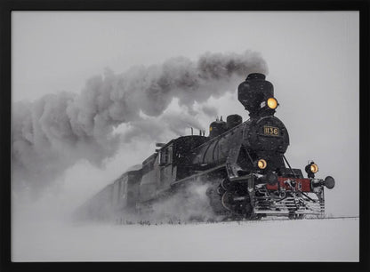 A dramatic black and white photograph of a classic steam train, number 1136, plowing through a heavy snowstorm, with its headlights glowing and a large plume of smoke trailing behind it. The image is presented within a silver frame. Print