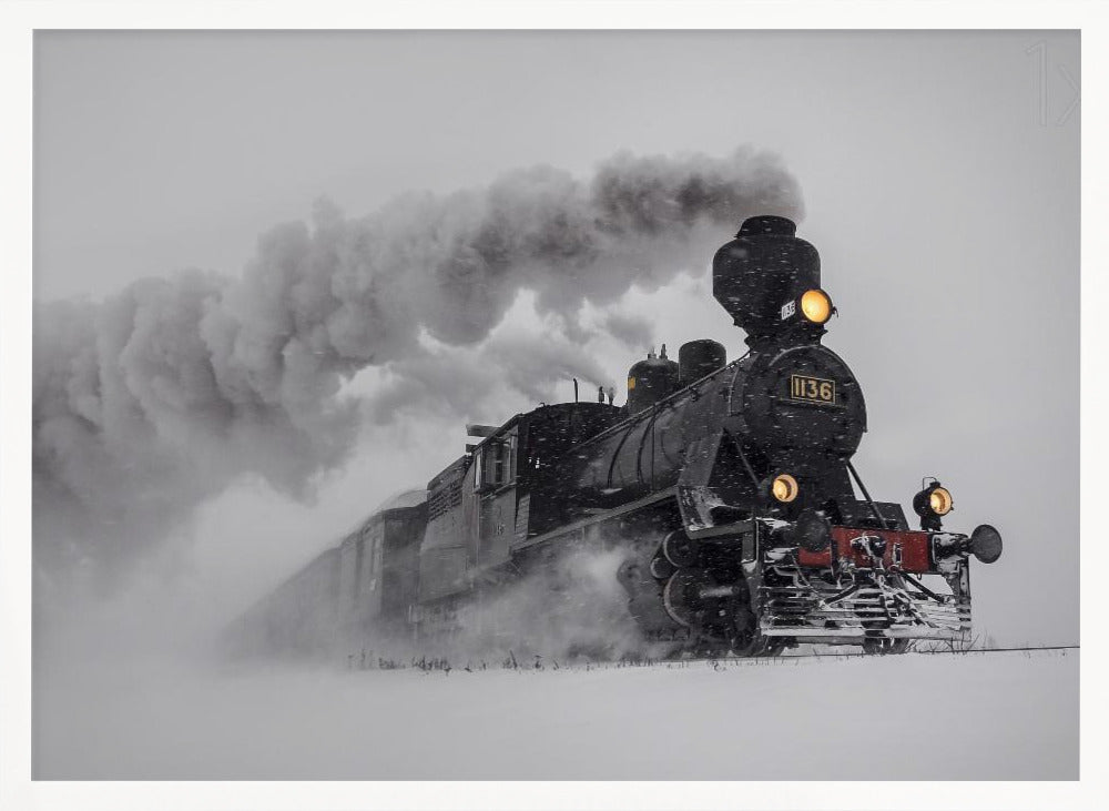 A dramatic black and white photograph of a classic steam train, number 1136, plowing through a heavy snowstorm, with its headlights glowing and a large plume of smoke trailing behind it. The image is presented within a silver frame. Print