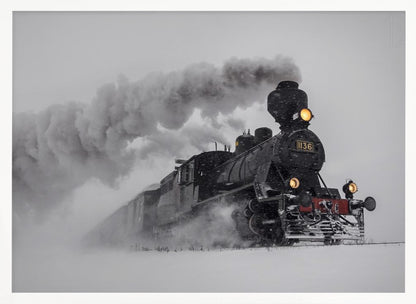 A dramatic black and white photograph of a classic steam train, number 1136, plowing through a heavy snowstorm, with its headlights glowing and a large plume of smoke trailing behind it. The image is presented within a silver frame. Print