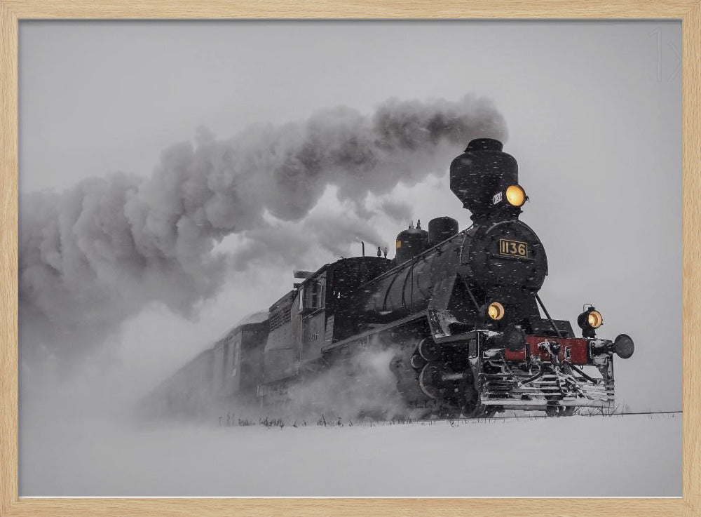 A dramatic black and white photograph of a classic steam train, number 1136, plowing through a heavy snowstorm, with its headlights glowing and a large plume of smoke trailing behind it. The image is presented within a silver frame. Print