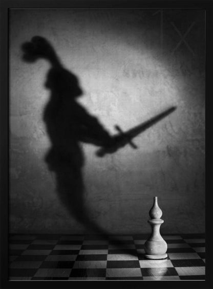 A black and white conceptual photograph of a single white chess piece on a checkerboard, casting a large, ominous shadow of a medieval knight holding a sword against a textured wall. Print