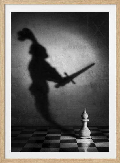 A black and white conceptual photograph of a single white chess piece on a checkerboard, casting a large, ominous shadow of a medieval knight holding a sword against a textured wall. Print