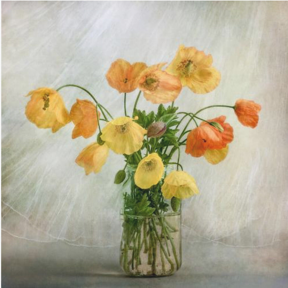 A soft-focus still life photograph of a bouquet of yellow and orange poppies in a clear glass jar, set against a delicate, light green textured background, all enclosed in a light wood frame. Print