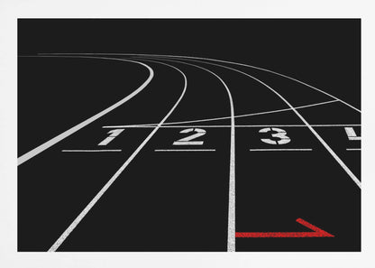 A framed, high-contrast photograph of a black running track's starting line. The lanes, marked with white lines, are numbered 1, 2, 3, and 4 and curve into the distance. A single red arrow points forward in the foreground, adding a pop of color to the monochrome scene. Poster