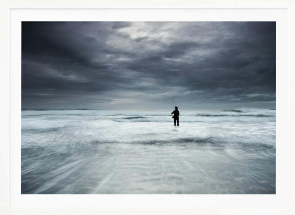 A moody, long-exposure photograph of a silhouetted fisherman standing in the churning white surf of the ocean under a dark, stormy sky, presented in a silver frame. Wall Art