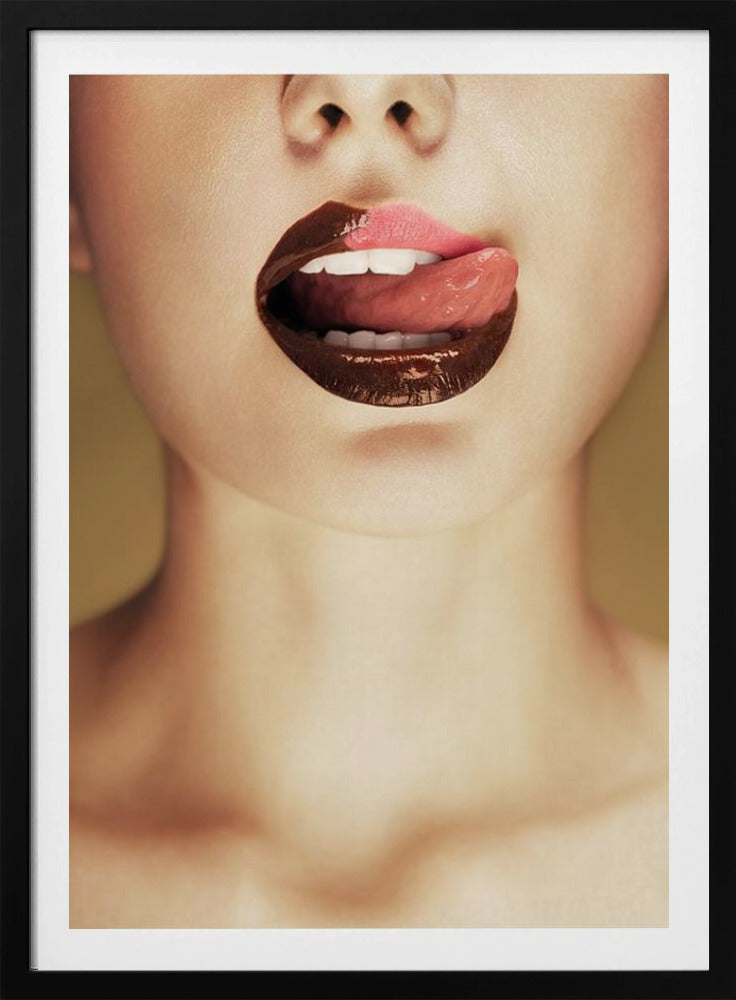 A close-up photograph of a woman's mouth with two-toned lipstick. The lips are mostly covered in glossy dark brown, with the upper right section in light pink. Her tongue is out, licking the pink part of her lip, revealing her white teeth. Print