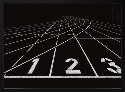 A framed, high-contrast graphic of a black running track from a low-angle perspective at the starting line. White lines delineate the lanes, with the numbers 1, 2, and 3 stenciled in the foreground. The track curves and recedes into the distance, creating a strong sense of perspective. Decor