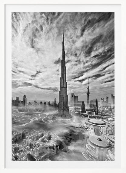A dramatic black and white high-angle photograph of the Burj Khalifa dominating the Dubai cityscape, with swirling clouds above and a light mist surrounding the buildings below, all enclosed in a black frame. Poster