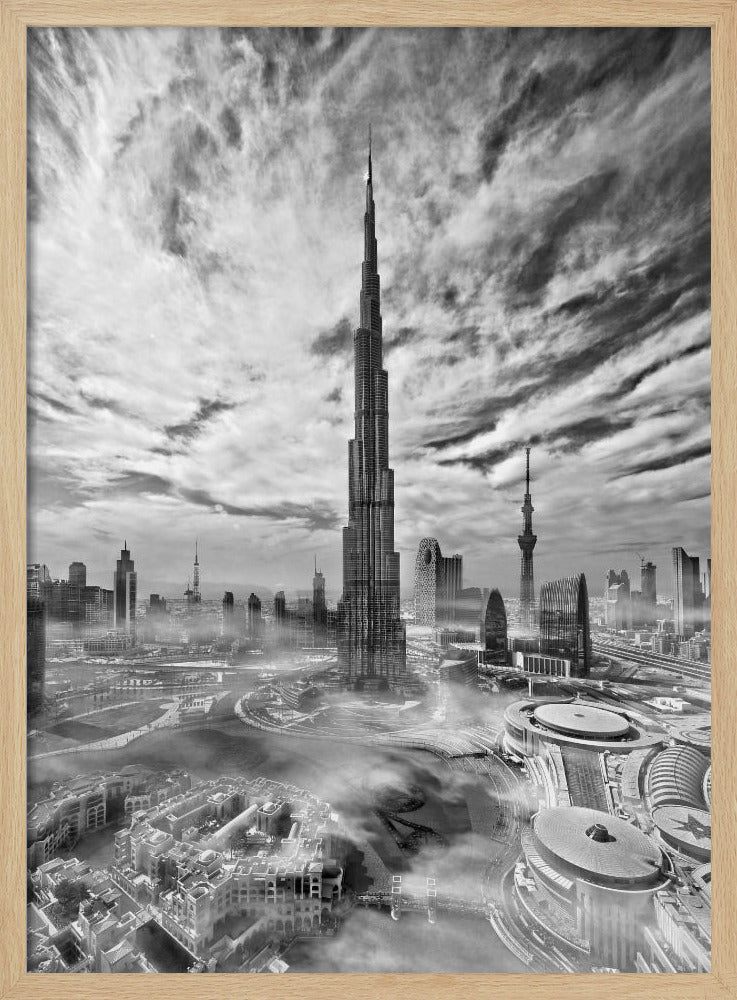 A dramatic black and white high-angle photograph of the Burj Khalifa dominating the Dubai cityscape, with swirling clouds above and a light mist surrounding the buildings below, all enclosed in a black frame. Poster
