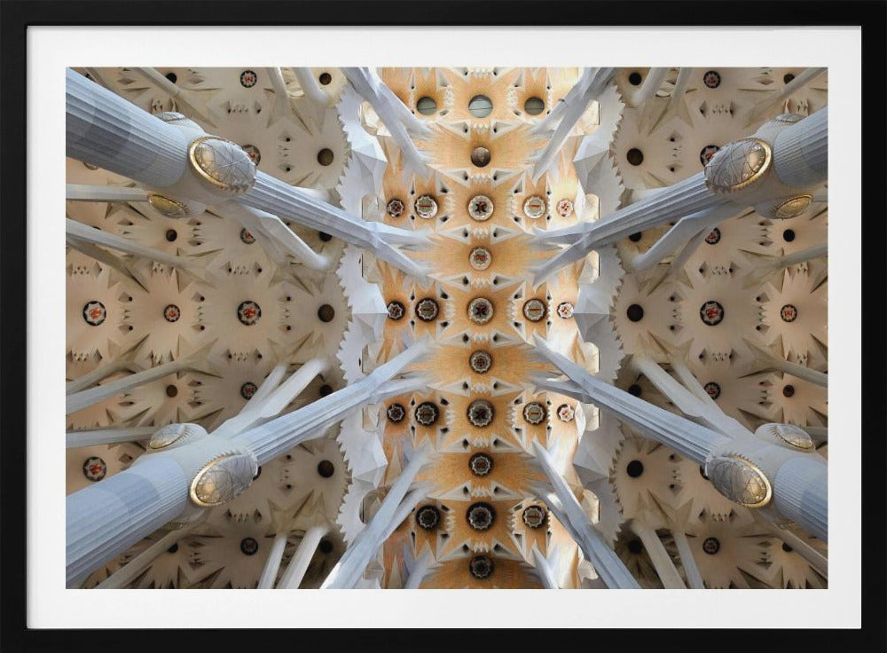 A symmetrical photograph looking directly up at the ornate, geometric ceiling of the Sagrada Familia. White, tree-like columns branch out to support the intricate vaulted ceiling, which is detailed with warm orange and gold starburst patterns. Decor