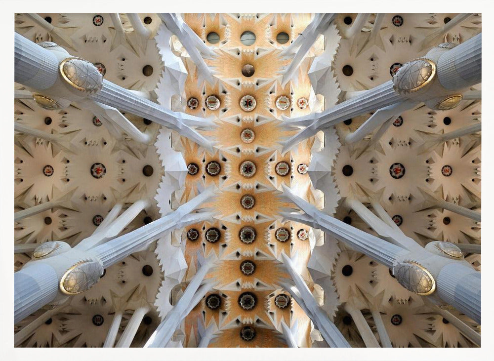 A symmetrical photograph looking directly up at the ornate, geometric ceiling of the Sagrada Familia. White, tree-like columns branch out to support the intricate vaulted ceiling, which is detailed with warm orange and gold starburst patterns. Decor