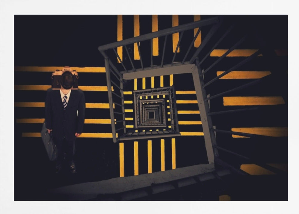 A surreal high-angle view looking down an infinite square spiral staircase with black steps and bold yellow stripes. On a landing stands a man in a dark suit and tie, holding a briefcase, with a vintage camera in place of his head. Artwork