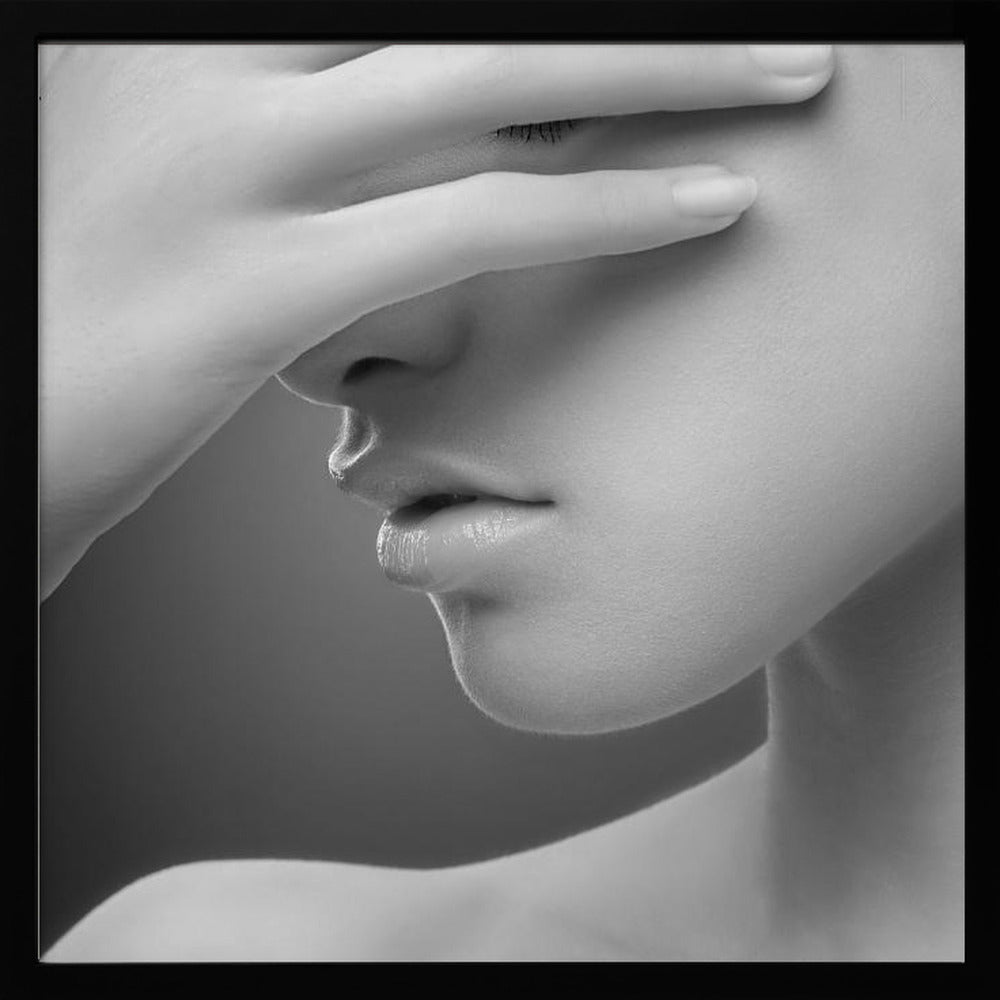 A close-up, black and white photograph of a woman's face. Her hand covers her eyes, revealing only the lower half of her face including her nose, lips, and chin. The image has a soft, sensual quality and is set within a light-colored wooden frame. Decor