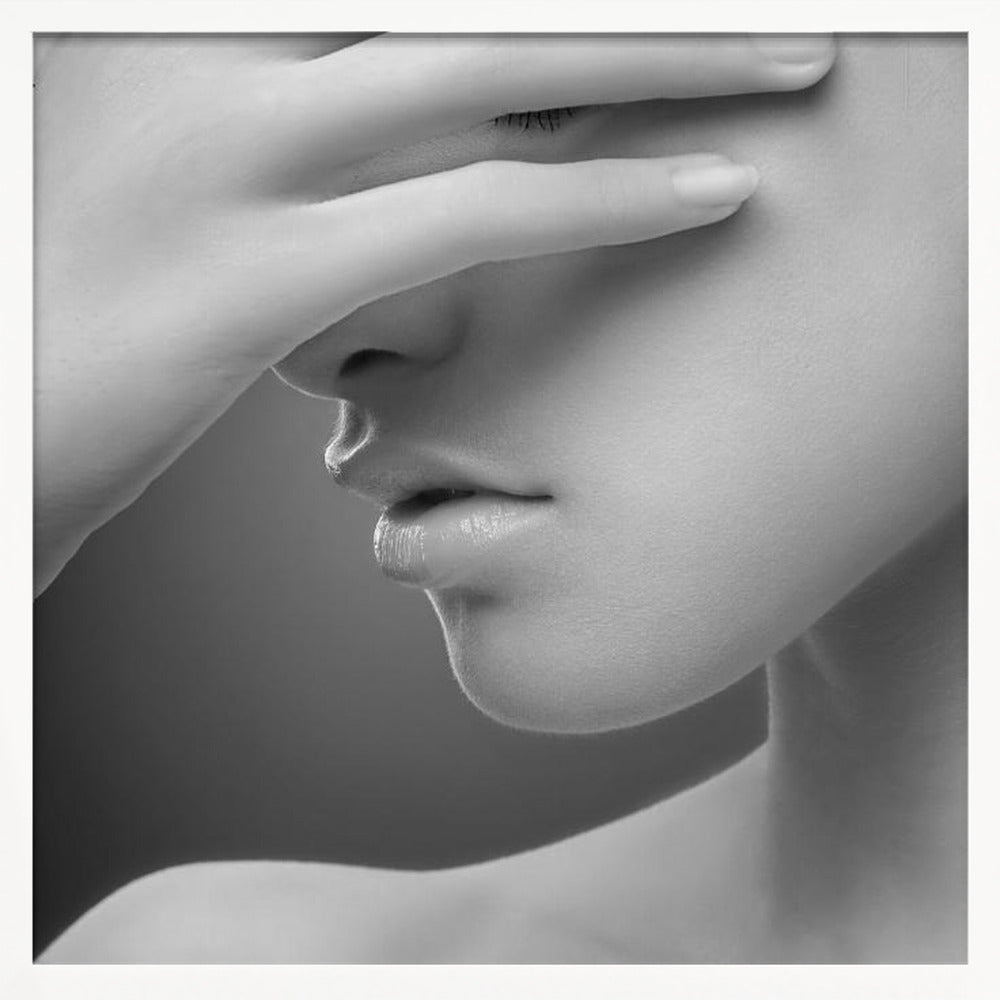 A close-up, black and white photograph of a woman's face. Her hand covers her eyes, revealing only the lower half of her face including her nose, lips, and chin. The image has a soft, sensual quality and is set within a light-colored wooden frame. Decor