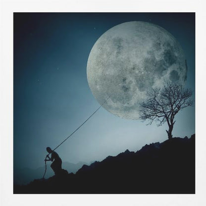 A surreal, framed artwork depicting a silhouette of a person on a dark, rocky hill at night, pulling a rope attached to a massive, detailed full moon, seemingly trying to pull it from the dark blue, star-dusted sky. A bare, silhouetted tree stands on the same hill. Artwork