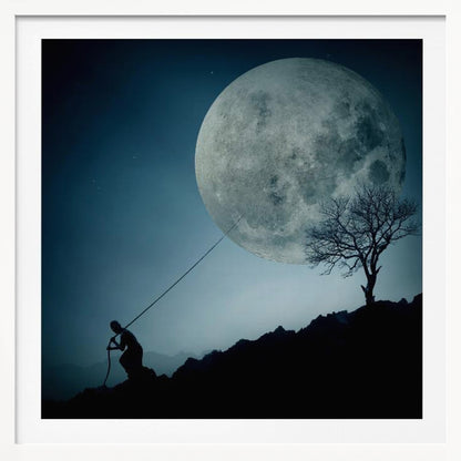 A surreal, framed artwork depicting a silhouette of a person on a dark, rocky hill at night, pulling a rope attached to a massive, detailed full moon, seemingly trying to pull it from the dark blue, star-dusted sky. A bare, silhouetted tree stands on the same hill. Artwork