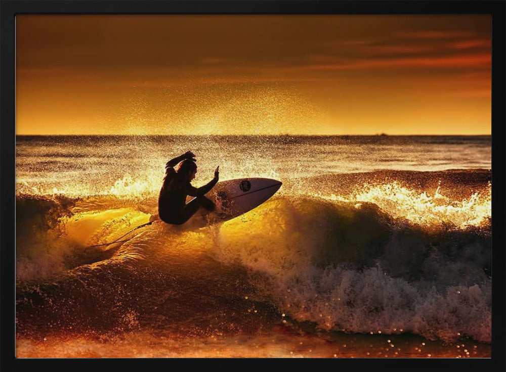 A silhouetted surfer carves a turn on a sun-kissed wave during a vibrant orange sunset, with golden light reflecting off the water and sea spray. Wall Art
